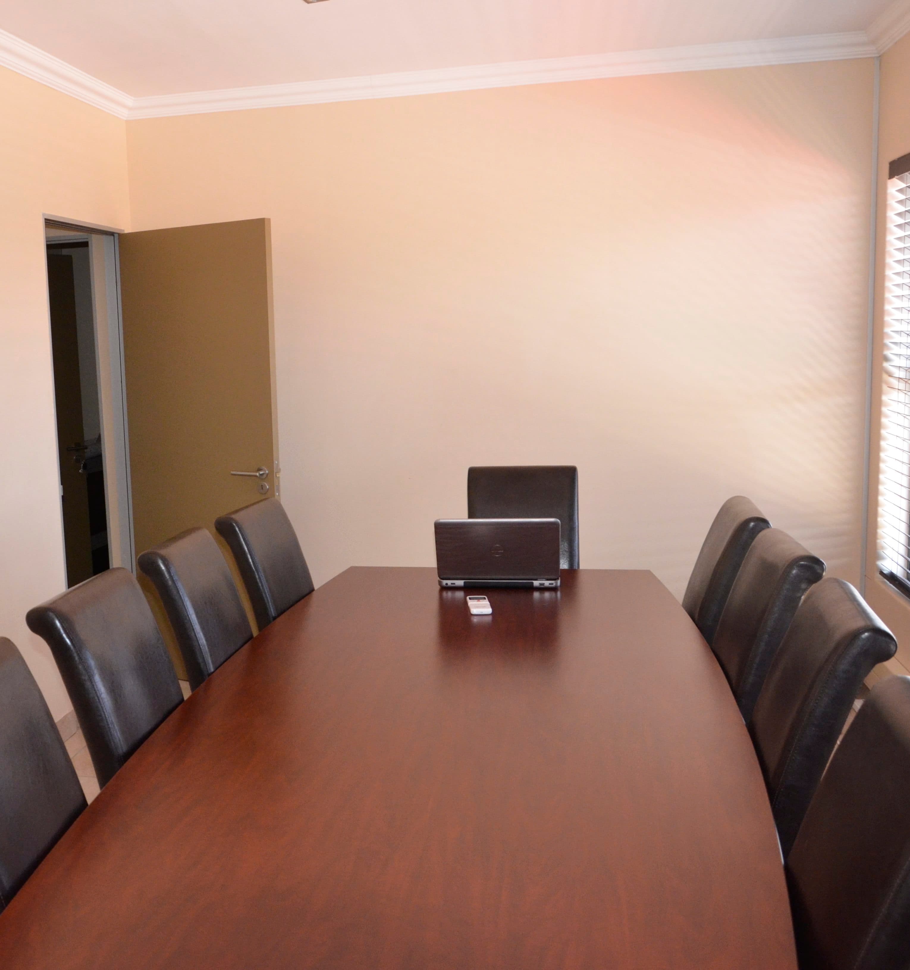 The conference room: a long wooden table lined with dark leather chairs