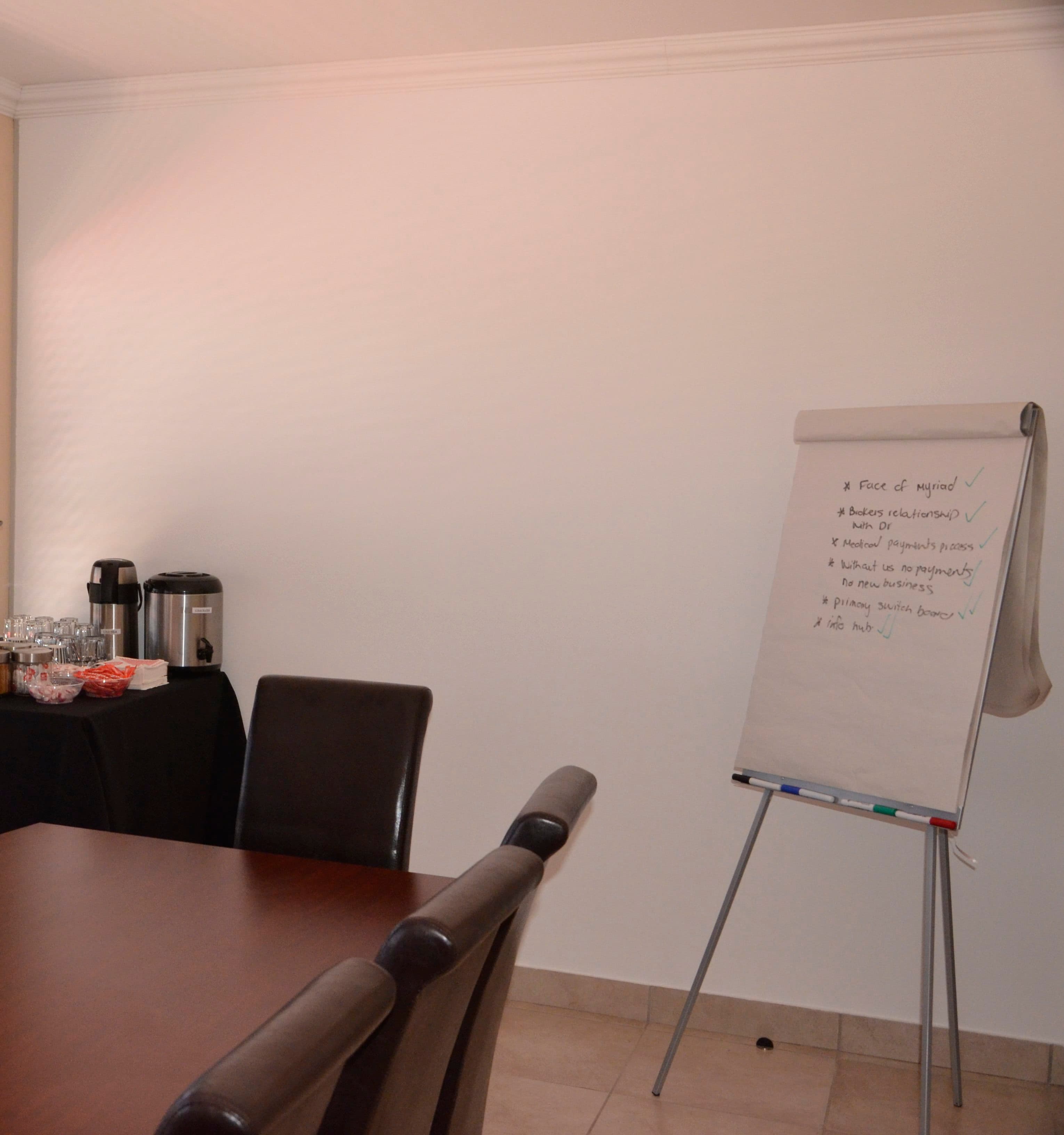 Flip chart on an easel next to a refreshment table with urns, glasses and snacks